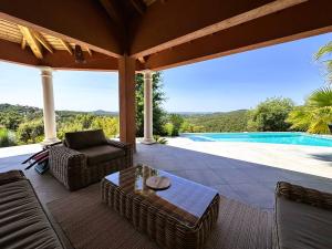a patio with chairs and a table and a pool at Villa Azur climatisée pour 6 personnes avec piscine et belle vue mer à La Londe les Maures in La Londe-les-Maures +30 photos