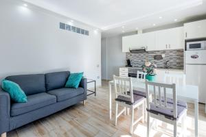 Una sala de estar con un sofá y una mesa con sillas. en 523 central Playa las Americas , Wi Fi Gratis y Piscina, en Csta Adje