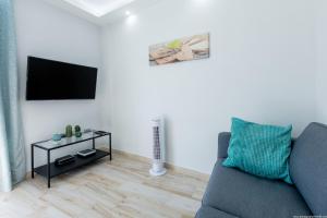 Una sala de estar con un sofá y un televisor. en 523 central Playa las Americas , Wi Fi Gratis y Piscina, en Csta Adje