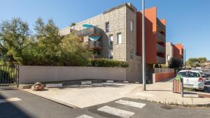 ein Gebäude mit einem auf einem Parkplatz geparkten Auto in der Unterkunft ALIZES BLEUS DE THAU 5 étoiles in Balaruc-les-Bains