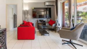 ein Wohnzimmer mit einem roten Stuhl und einem TV in der Unterkunft ALIZES BLEUS DE THAU 5 étoiles in Balaruc-les-Bains