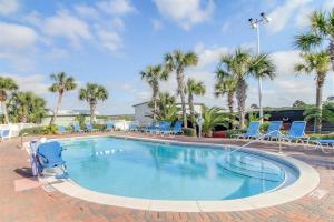 a swimming pool with blue chairs and palm trees at Beautiful Beach Front Paradise at Pinnacle Port B2-608! in Panama City Beach