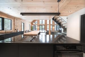 a kitchen with a black counter top and wooden ceilings at Le Mitik Tremblant - SPA - LACS - PLAGES - JEUX in Saint-Rémi-dʼAmherst