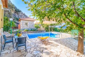 a patio with a table and chairs and a pool at Villa Palataki II in Kardamyli