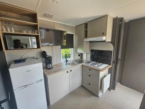 a small kitchen with white cabinets and a white refrigerator at loggia 29 in Biville-sur-Mer