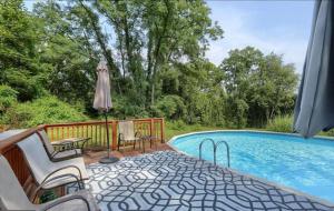 a swimming pool with two chairs and an umbrella at Forest Tree Log Cabin in Middletown