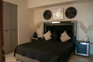 a bedroom with a black bed with pillows on it at Malecón Love in Mazatlán +35 photos