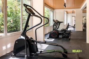 a gym with treadmills and ellipticals in a room with windows at Jardim das Palmeiras II - Multipropriedade in Ubatuba