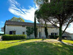 a large white house with a tree in the yard at Cottage Coeur des Vignes in Fargues