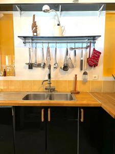 a kitchen sink with utensils hanging on a wall at Cottage Coeur des Vignes in Fargues