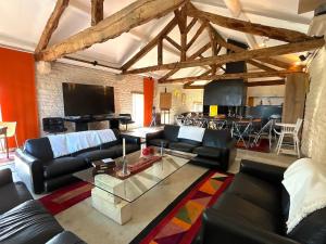 a living room with leather couches and a tv at Cottage Coeur des Vignes in Fargues