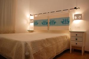 ein Schlafzimmer mit Bett, Kommode und Lampen in der Unterkunft La Terrazza sul Mare in San Teodoro