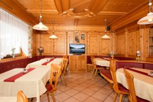 restauracja ze stołami i krzesłami oraz telewizorem w obiekcie Pension Brugghof w mieście San Giovanni in Val Aurina