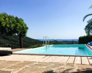 a large swimming pool with a wooden deck next to it at Villa Cosy pour 6 personnes avec piscine privée et vue panoramique sur les îles et les collines à La Londe les Maures in La Londe-les-Maures
