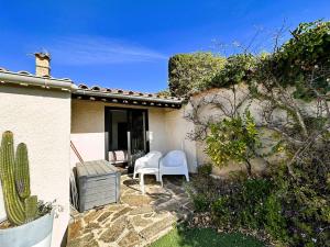 a patio with two white chairs and a house at Villa Cosy pour 6 personnes avec piscine privée et vue panoramique sur les îles et les collines à La Londe les Maures in La Londe-les-Maures +18 photos
