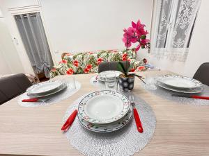 サンレモにあるSANREMO - Affittasi Elvi Home, appartamento con aria condizionata centralissimo a pochissima distanza da Ariston, Casinò e dal mareのダイニングルームテーブル(皿、赤の調理器具付) +9枚の写真