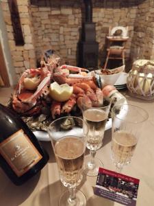 einen Tisch mit Gläsern Champagner und einem Teller mit Meeresfrüchten in der Unterkunft Le clos de la Pommeraie Carly in Carly