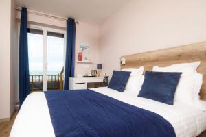 a bedroom with a large bed with blue and white pillows at Saint Aubin Logis Hôtel & Restaurant in Saint-Aubin-sur-Mer