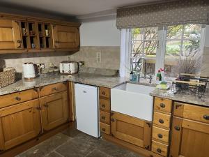 a kitchen with wooden cabinets and a white sink at Corner Cottage in Knaresborough