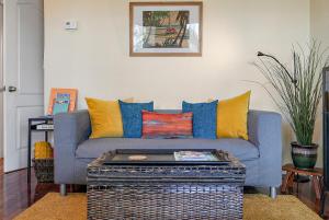 a living room with a blue couch with colorful pillows at Wine-Dine-Sunshine Cozy Flat in The Heart of DTSP in St Petersburg