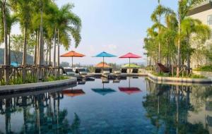una piscina con ombrelloni, sedie e palme di Mida Grand Resort Phuket a Ban Lum Fuang