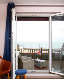 a room with a balcony with a view of the ocean at Saint Aubin Logis Hôtel & Restaurant in Saint-Aubin-sur-Mer