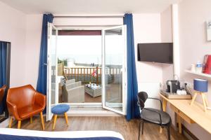 a bedroom with a sliding glass door to a balcony at Saint Aubin Logis Hôtel & Restaurant in Saint-Aubin-sur-Mer