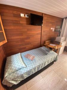 a bedroom with a bed and a tv on a wall at Residencial Chalés Riviera in Matinhos