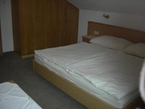 a bedroom with a large bed with white sheets at Haus Mooshof in Lermoos