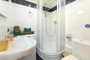 a white bathroom with a shower and a sink at The Wenceslas Loft in Prague