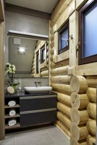 a bathroom with a sink and a wooden wall at Avalon Resort & SPA in Miskolctapolca