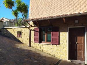a brick house with pink shutters and a window at Masaya house in Ronciglione