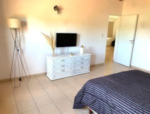 a bedroom with a television and a dresser with a bed at El Retiro CASA 3 DORMITORIOS in Villa El Chocón