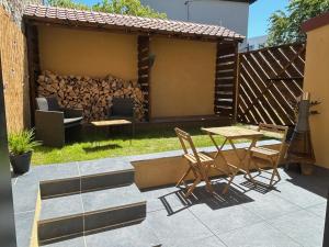 un patio con tavolo, sedie e un mucchio di legno di Art des sens - SPA et Sauna privatifs a Boulogne-sur-Mer