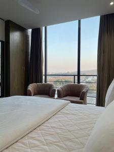 a bedroom with a large bed and two chairs at Sense Luxury II - 2 bed Apartment in Islamabad