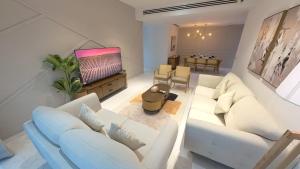 a living room with white furniture and a flat screen tv at Eaton Residence KLCC - JD HOME in Kuala Lumpur