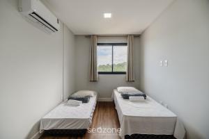 Dos camas en una habitación con ventana. en Apto 2H c/ parrilla a 750m de la playa RVN2003, en Itapema