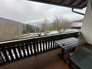 eine Bank auf einem Balkon mit Blick auf einen schneebedeckten Berg in der Unterkunft Uriges Apartment + Schönblick + mitten im Bayerischen Wald + WLAN kostenfrei in Schöfweg