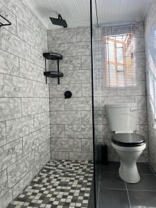 a bathroom with a toilet and a tiled floor at The Hideaway Cabin in Pretoria +26 photos