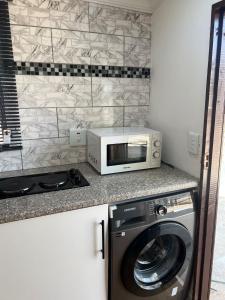 a kitchen with a microwave and a washing machine at The Hideaway Cabin in Pretoria