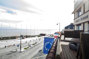 a flag on top of a building next to the ocean at Saint Aubin Logis Hôtel & Restaurant in Saint-Aubin-sur-Mer