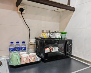 a microwave on a counter with cups and water bottles at Urban Oasis Apartment 5 in Melaka