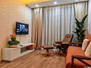 a living room with a tv and a couch and chairs at Urban Oasis Apartment 5 in Melaka