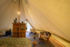 a bedroom with a tent with a bed and a chair at Glampingtent Camping Namasté in Berlicum