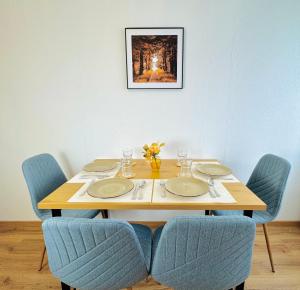 a wooden table with chairs and plates and a picture at Katy's Cozy Corner CityCenter in Graz