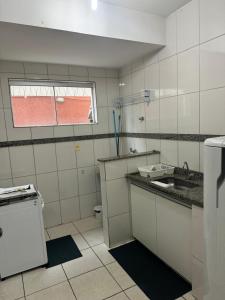 a white kitchen with a sink and a window at Aconchegante Apartamento in Lavras +2 photos