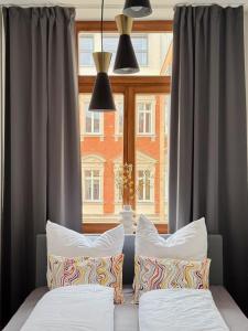 a bed with two pillows in front of a window at Feinzeit Lovely Lou - renovierter Altbau, Design, Zentrum! in Bamberg