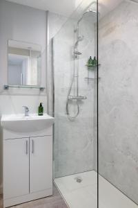 a white bathroom with a shower and a sink at Contemporary House Llanelli in Llanelli