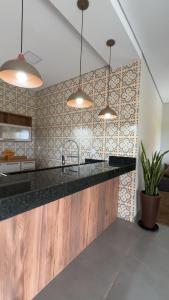 a kitchen with a counter with three pendant lights at Rancho do Tingo em Felixlândia mg in Felixlândia +76 photos