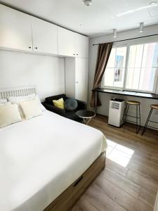 a bedroom with a large white bed and a couch at Stylish City Centre Studio - Grand Central House in Gibraltar